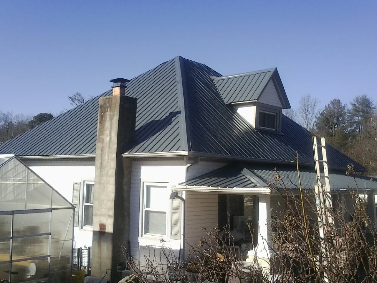Dark blue standing seam metal roof on a white farmhouse with dormer — Slate & Tile Roof Repair by Roofing Brothers in Peoa