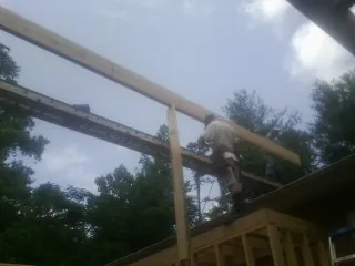 Carpenter setting a ridge beam over a new addition frame — Ice Dam Removal by Roofing Brothers in Peoa