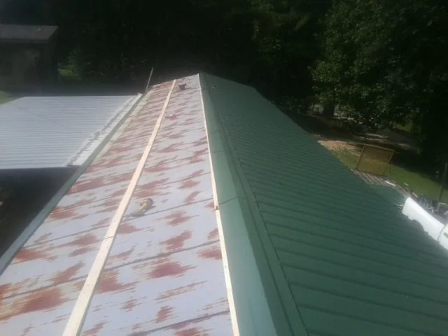 Old rusted panels beside newly installed green metal roofing — Wind Damage Roof Repair by Roofing Brothers in Peoa