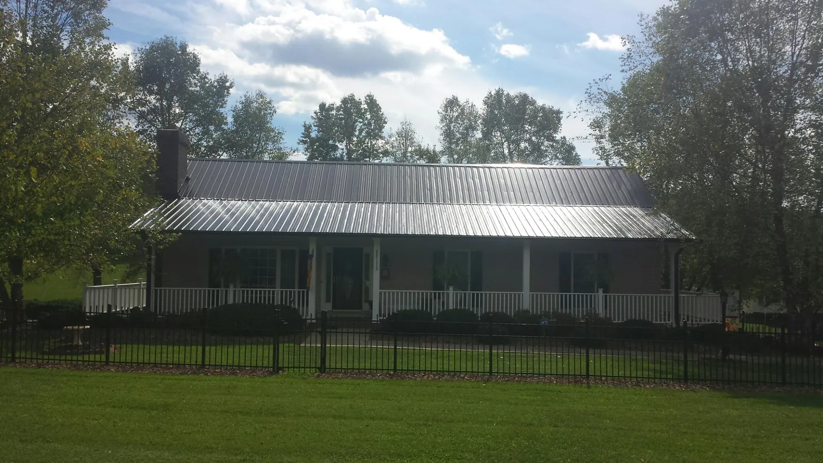 Gray metal roof on a brick ranch with a full width front porch — Gutter Guard Installation work by our crew in Peoa