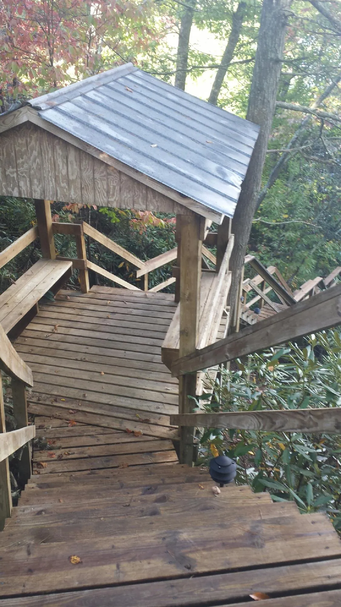 Metal roofed shelter over wooden steps on a wooded walkway — Skylight Repair & Installation work by our crew in Peoa