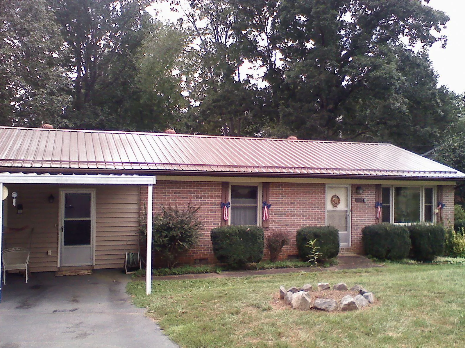 Bronze metal roof and carport on a brick ranch home — Roof Repair work by our crew in Peoa